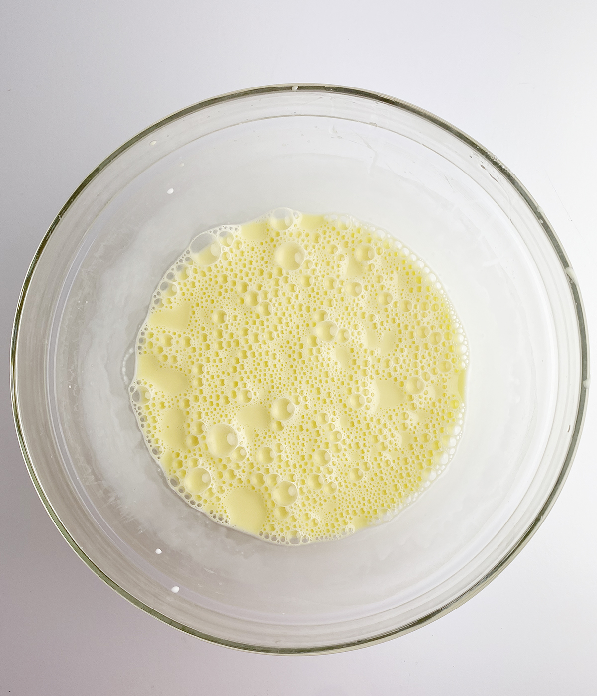 Frothy egg and cream mixture in a mixing bowl.