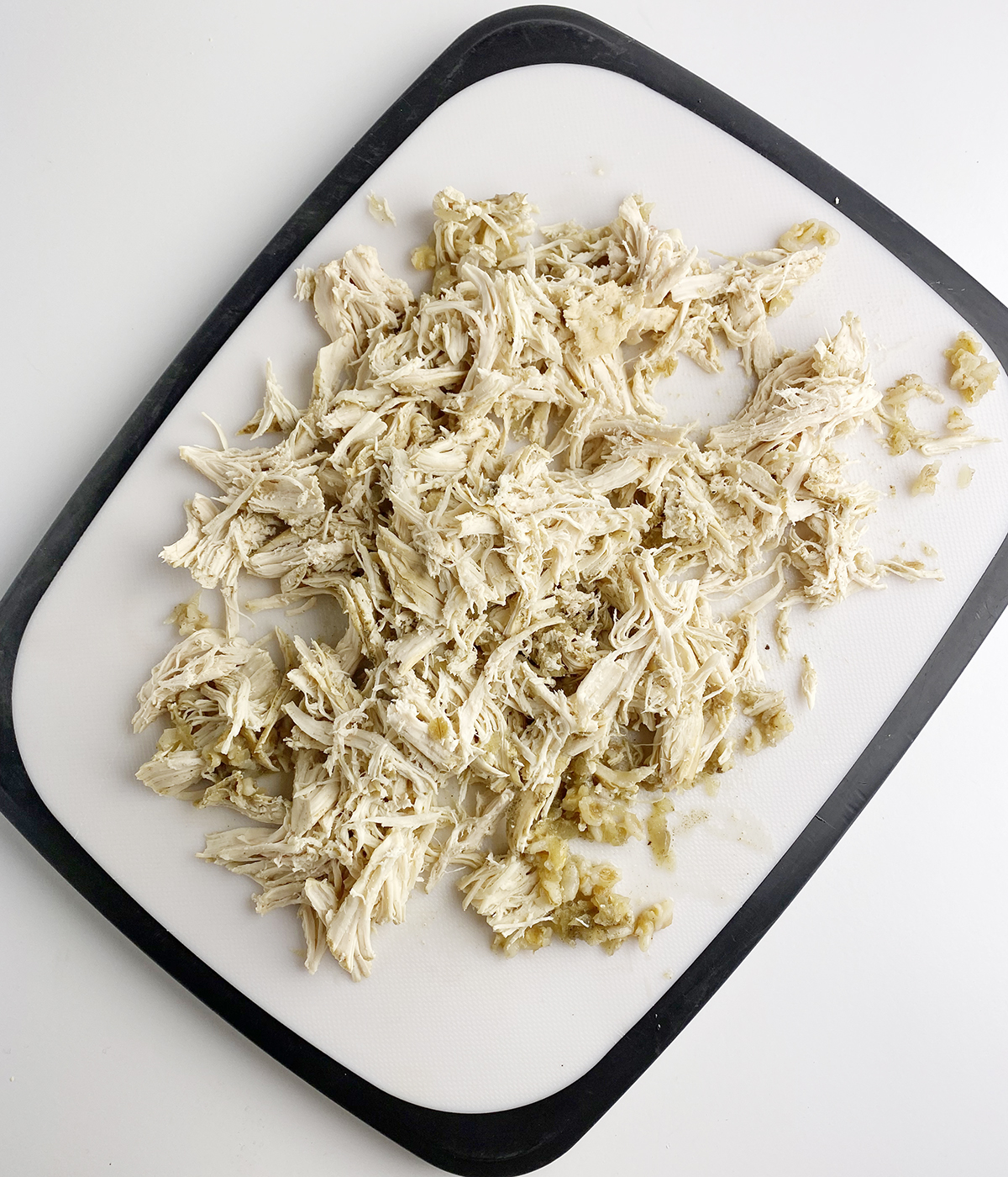 Shredded cooked chicken on a cutting board.