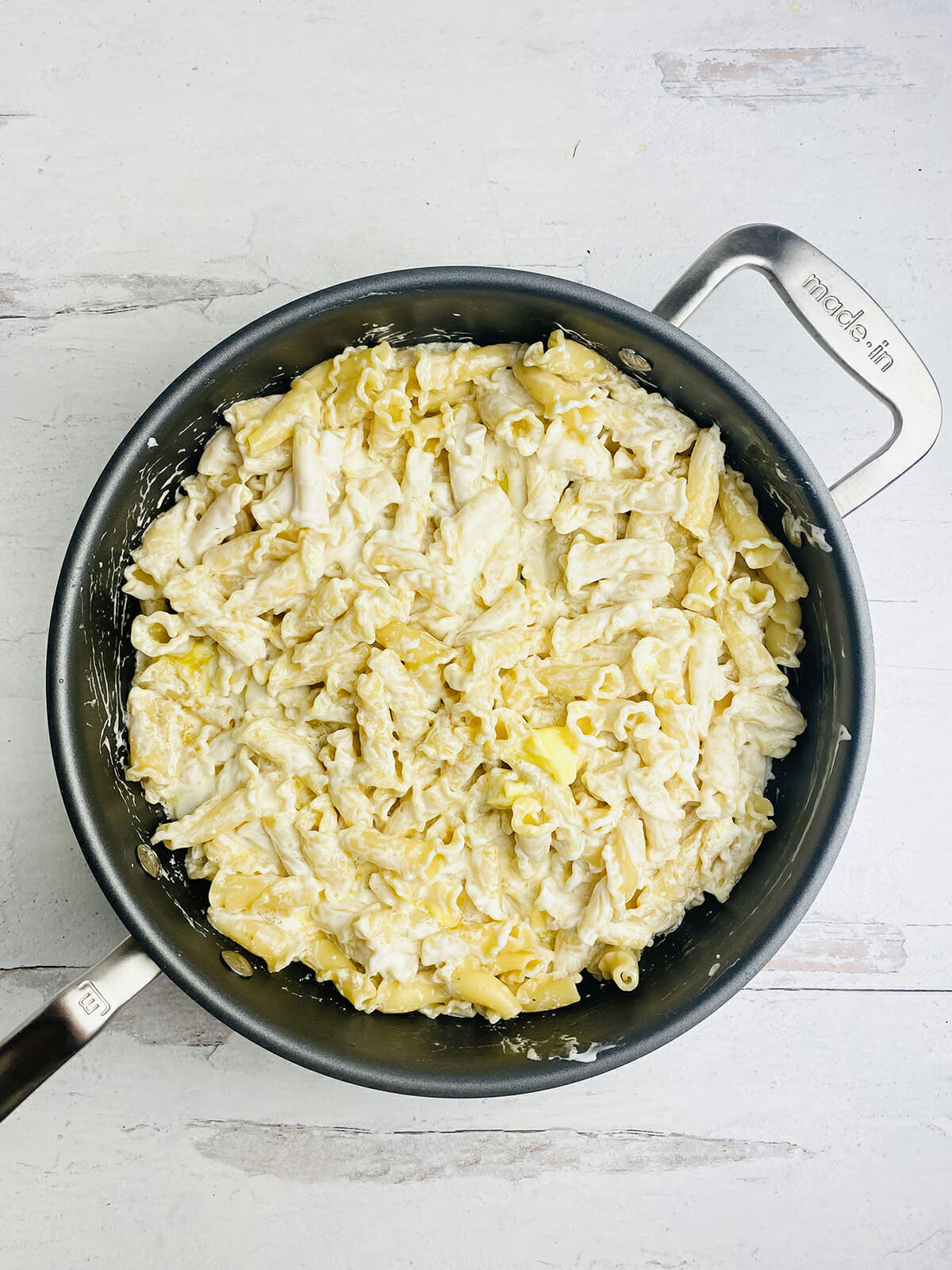 Sour cream and butter stirred into pasta in a pot.