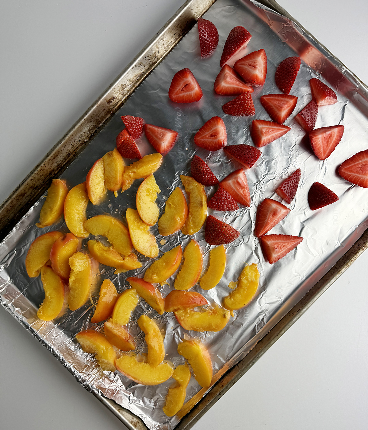 Frozen peaches and strawberries on a tray.