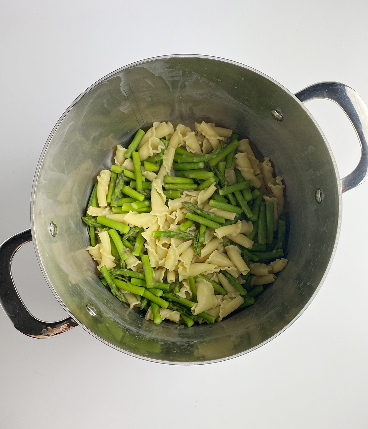 Pasta and asparagus pieces in a pot.