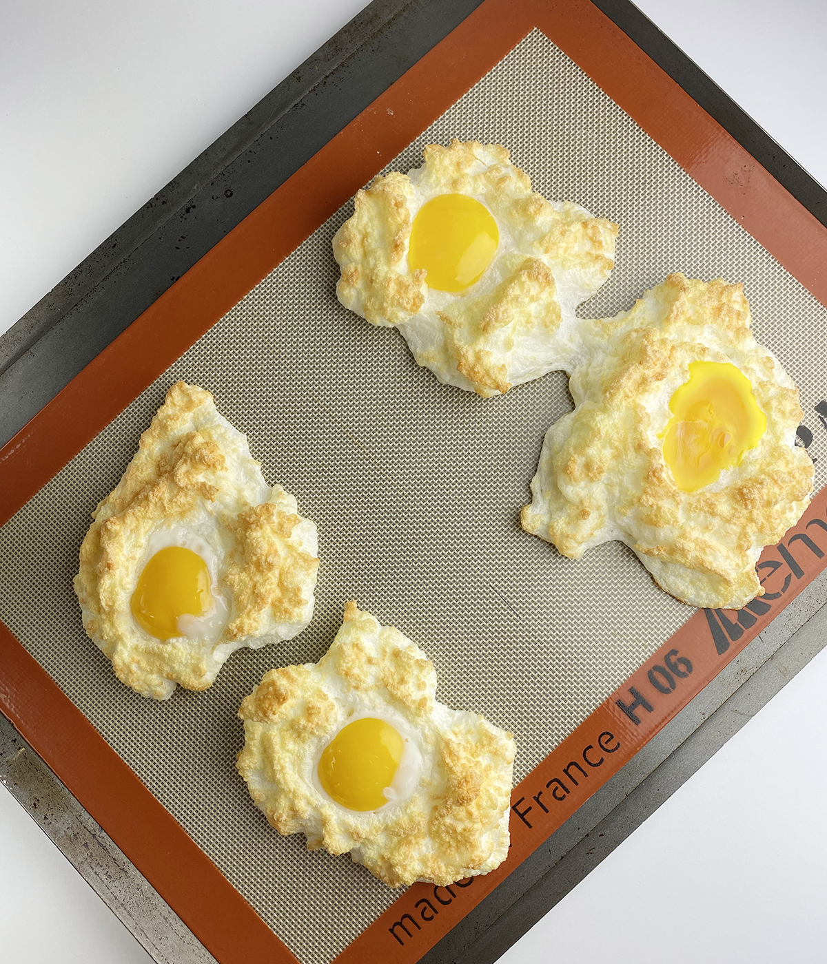 Fully baked eggs in clouds on a cookie sheet.