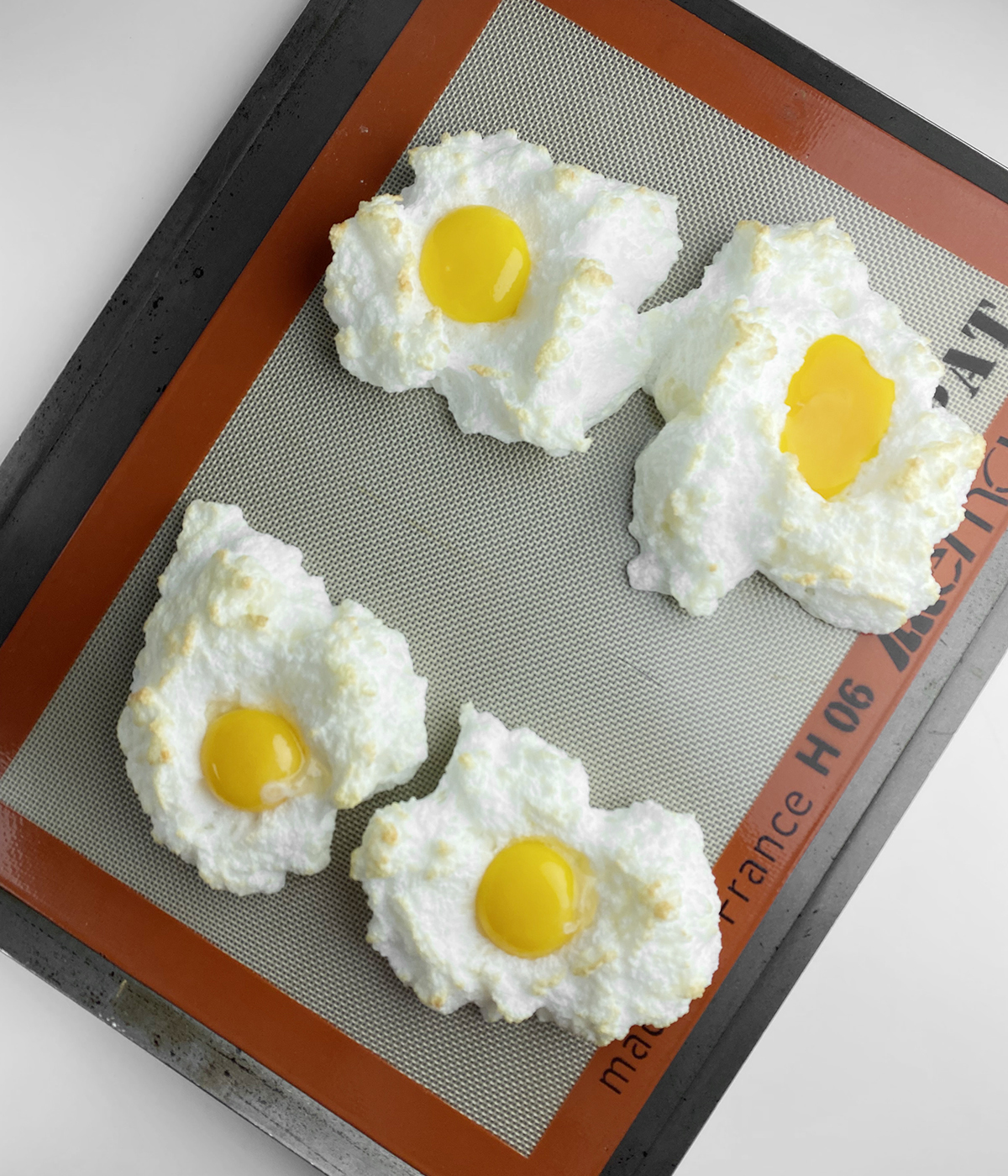 Partially baked eggs in clouds with egg yolks nestled in the clouds.