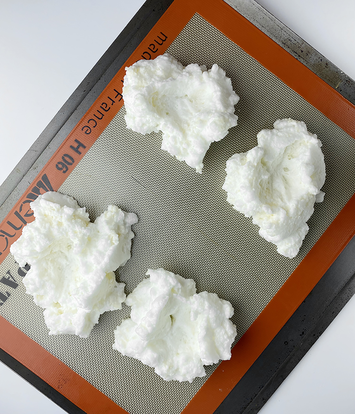 Whipped egg whites for eggs in clouds on a cookie sheet.