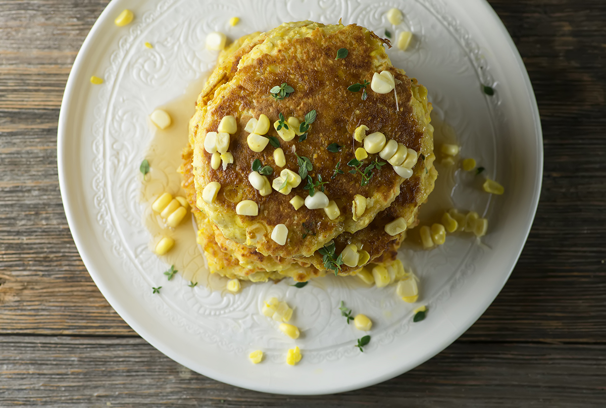 Fresh Corn johnny cakes on a plate on a wooden counter.
