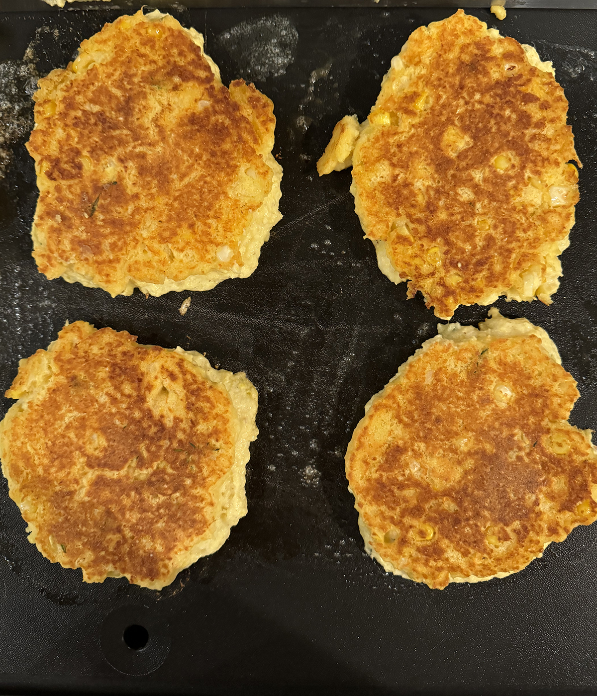 Johnny cakes cooking on a griddle.