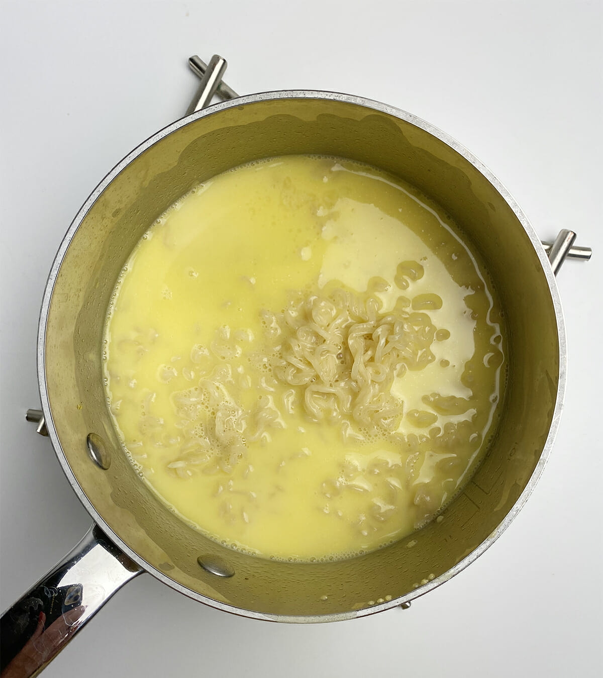 Ramen cooking in a pot with melted American Cheese.