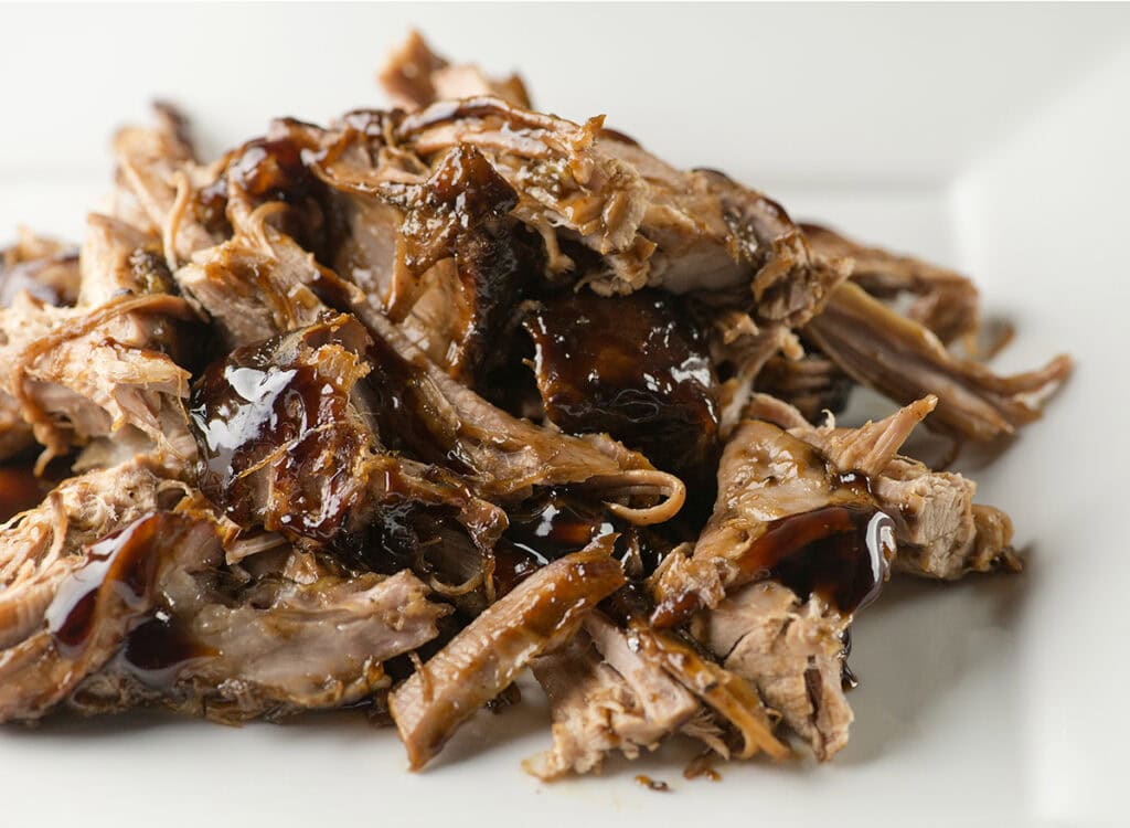 Pile of slow cooker brown sugar pulled pork on a plate.