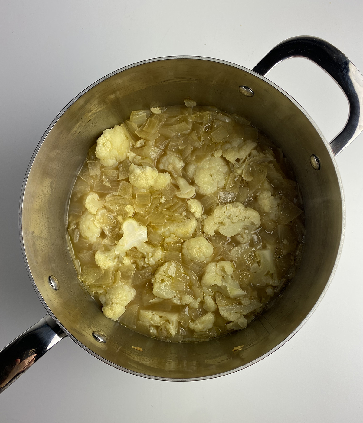 Cooked cauliflower and onions in a pot.