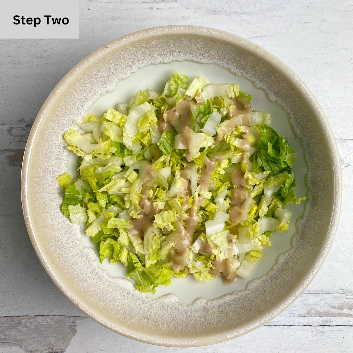 Chopped romaine lettuce with Caesar dressing in a bowl.