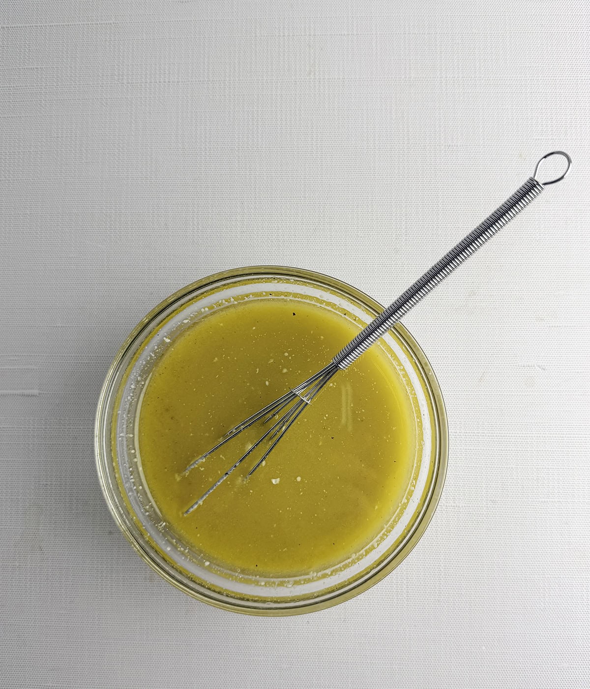 Mustard dressing in a small bowl with a whisk.