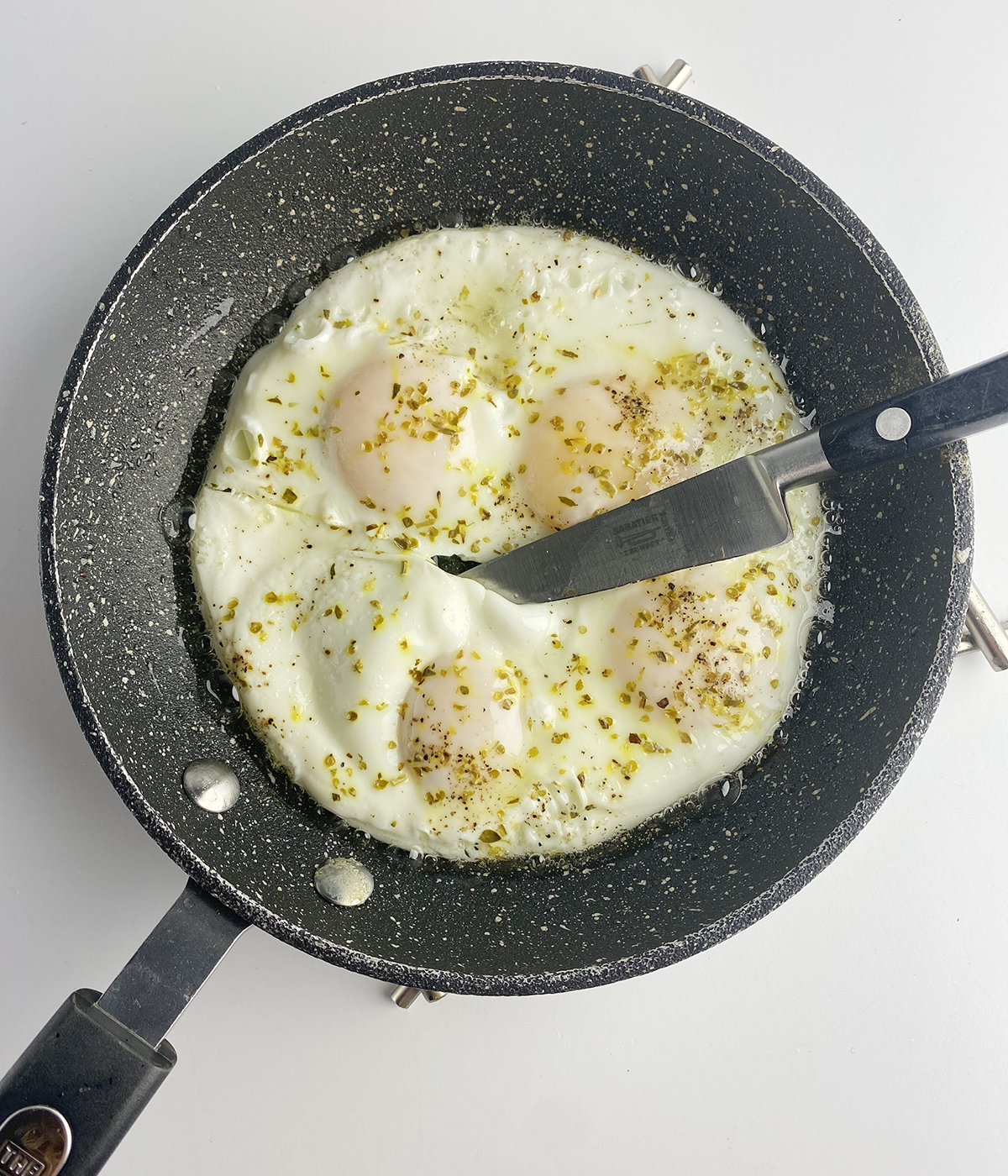 Perfect fried eggs in a skillet being cut apart.