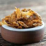 Potato Peel Chips in a bowl on a wooden counter.