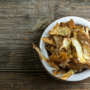 Potato Peel Chips in a bowl on a wooden counter.