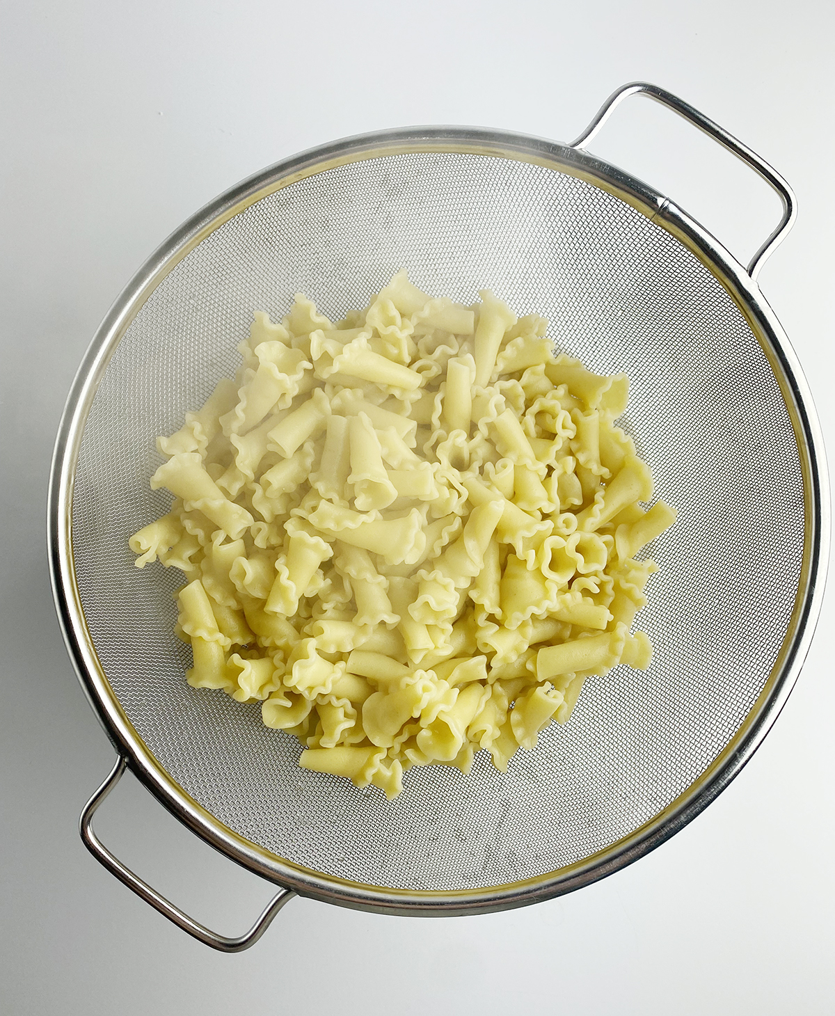 Pasta draining in a strainer.