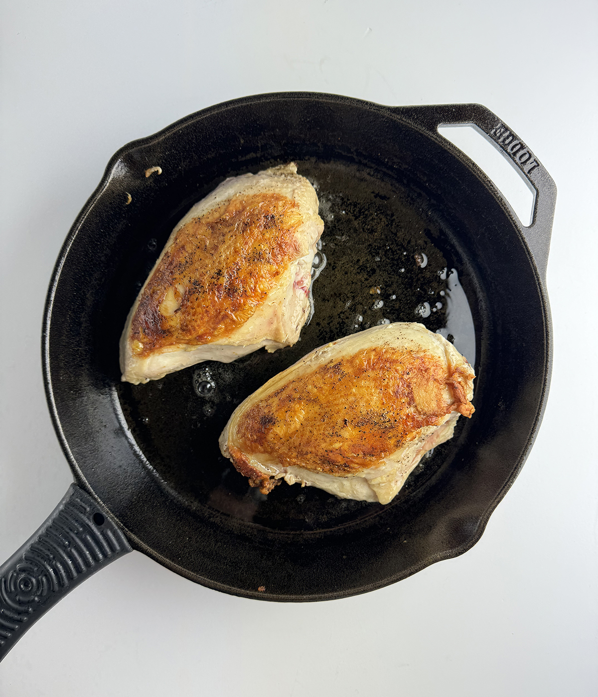 Seared chicken breasts in a skillet.