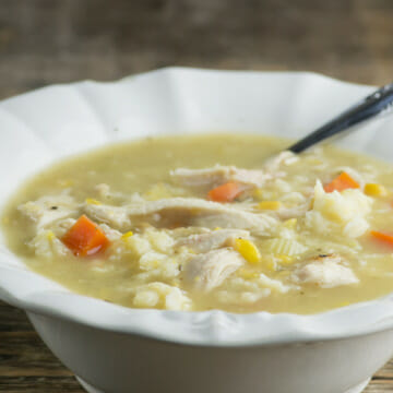 Bowl of chicken soup with baby dumplings with a spoon.