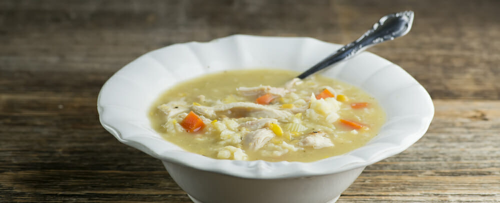 Bowl of chicken soup with baby dumplings with a spoon.