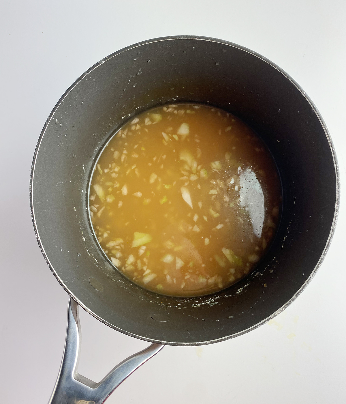 Chicken broth with veggies in a pot.