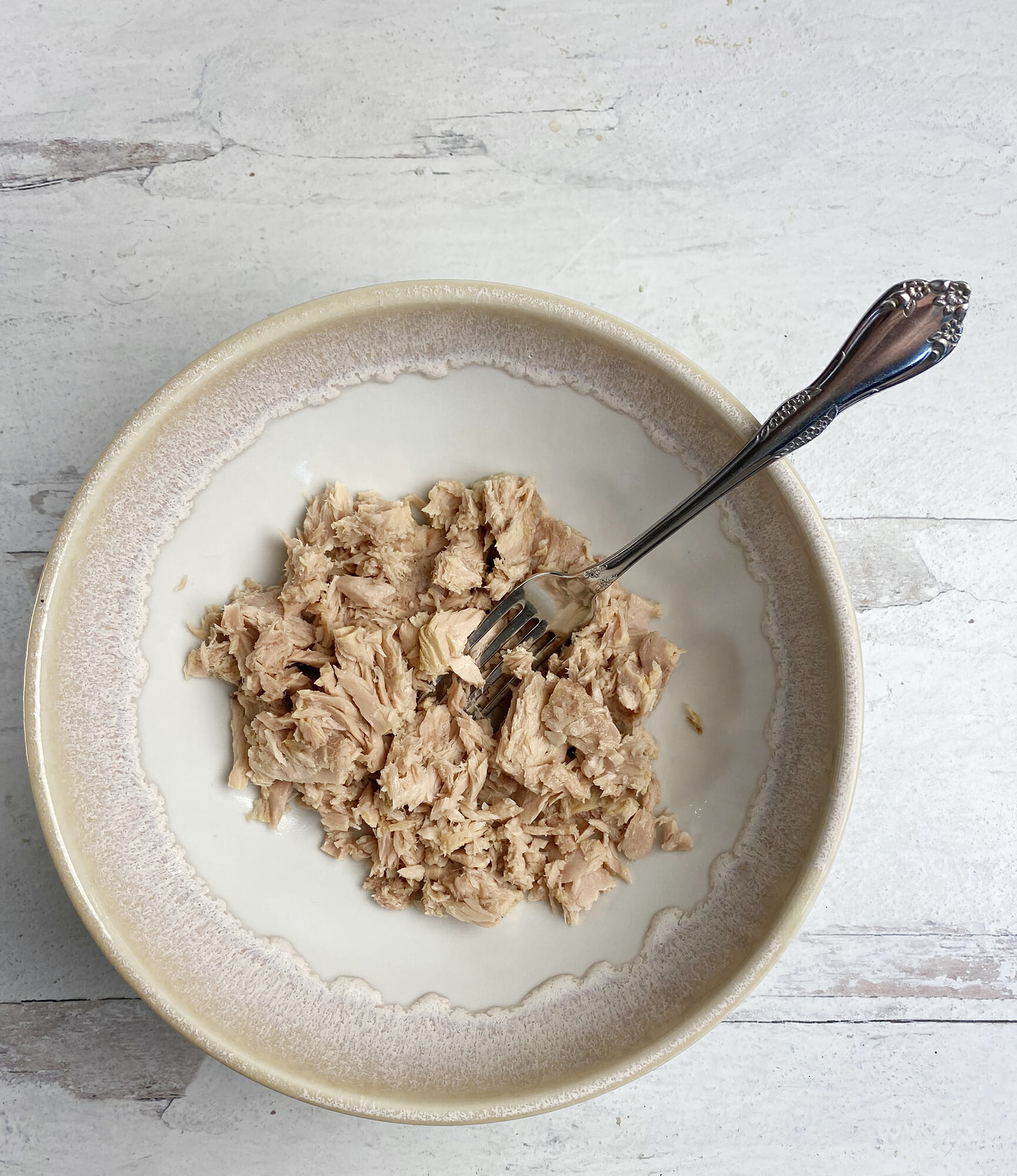 Flaked tuna fish in a bowl with a fork.