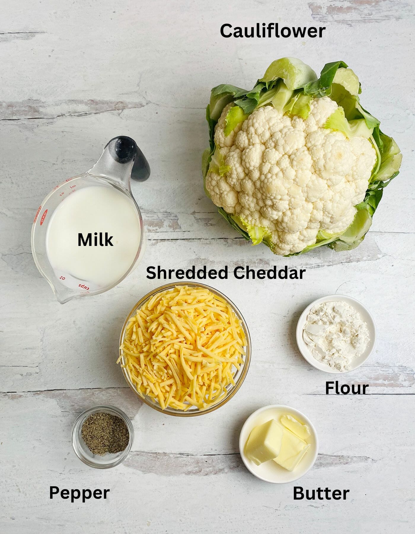 Cheesy cauliflower casserole ingredients on a wooden counter.