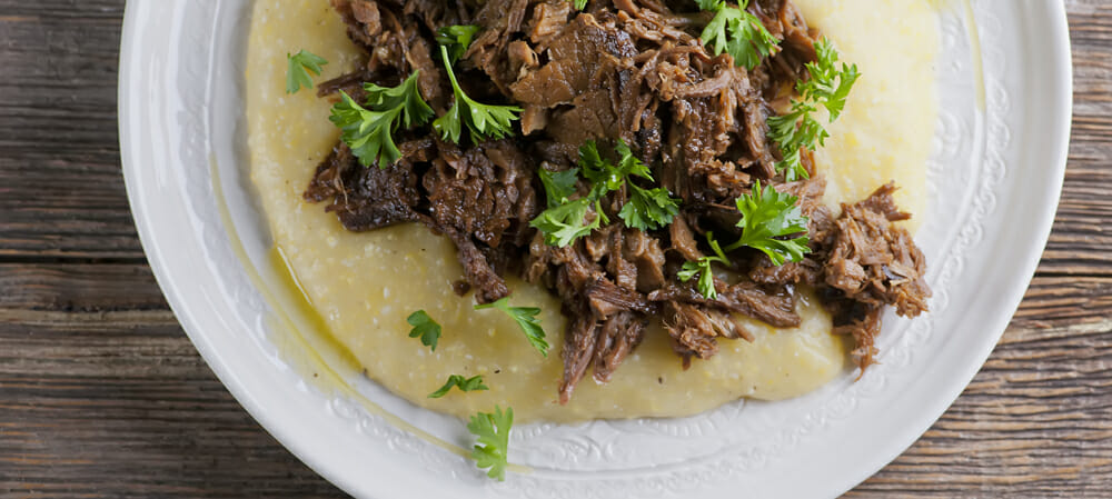 Mississippi Roast Slow Cooker Mississippi Pot Roast on a plate with grits.