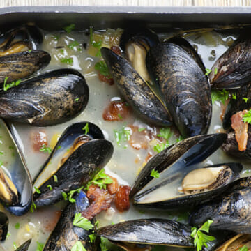 Oven steamed mussels in a roasting pan.