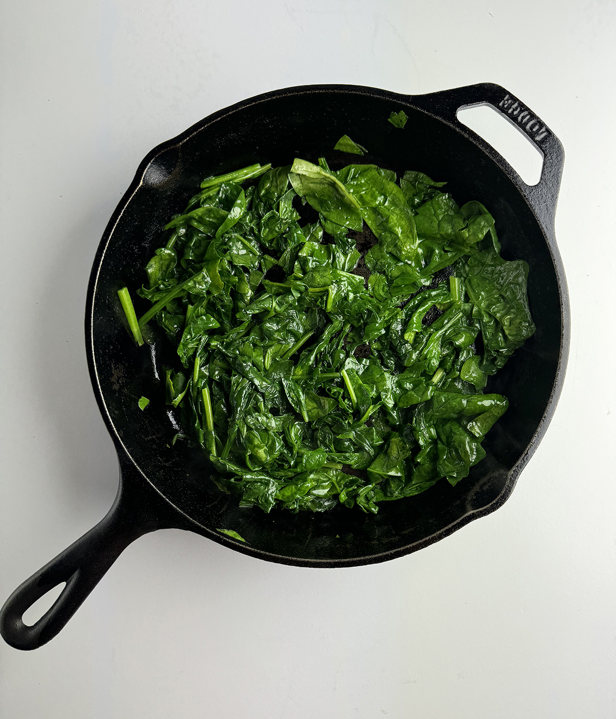 Cooked baby spinach in a skillet.