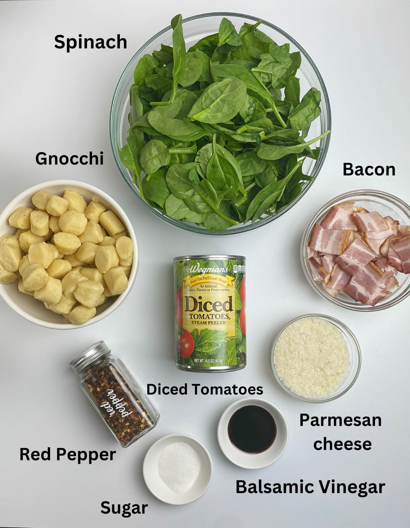 Gnocchi with bacon and spinach ingredients on a white counter.