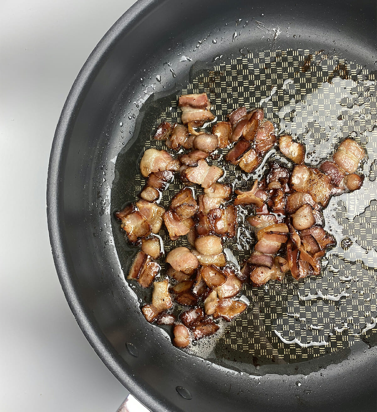 Chopped cooked bacon in a skillet.