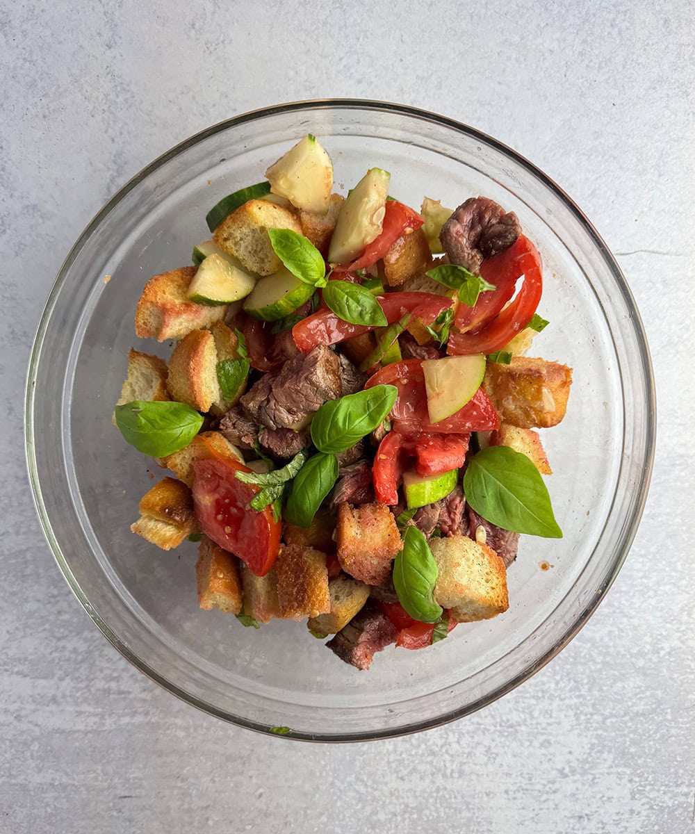 Steak Panzanella Salad marinating in a bowl.