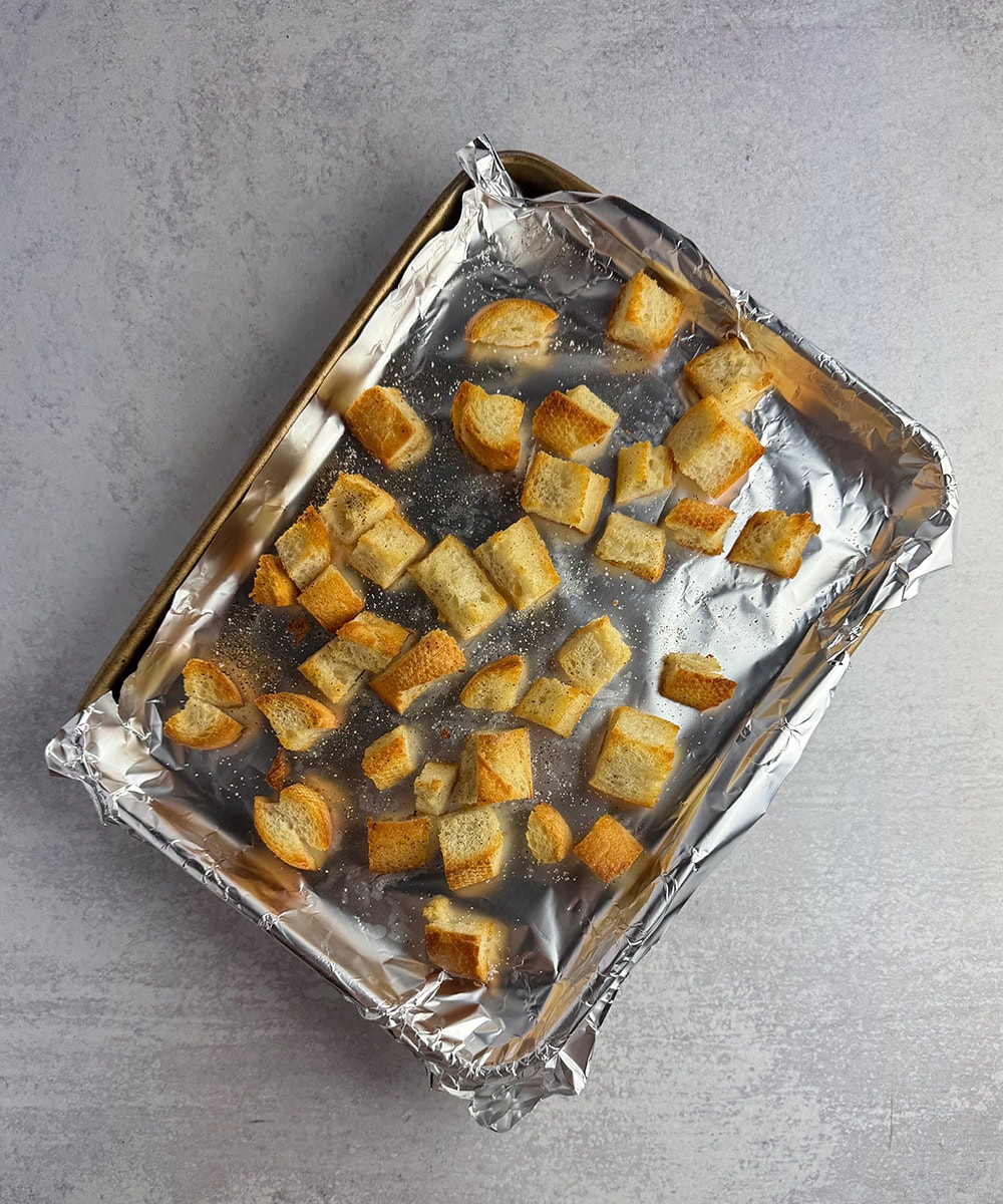 Toasted bread cubes on a baking sheet.