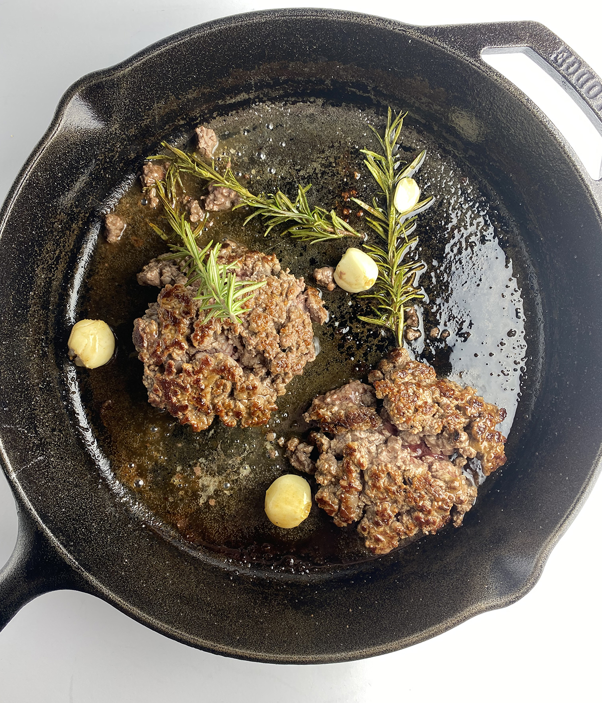 Seared steak tartare cooking in a cast iron skillet.