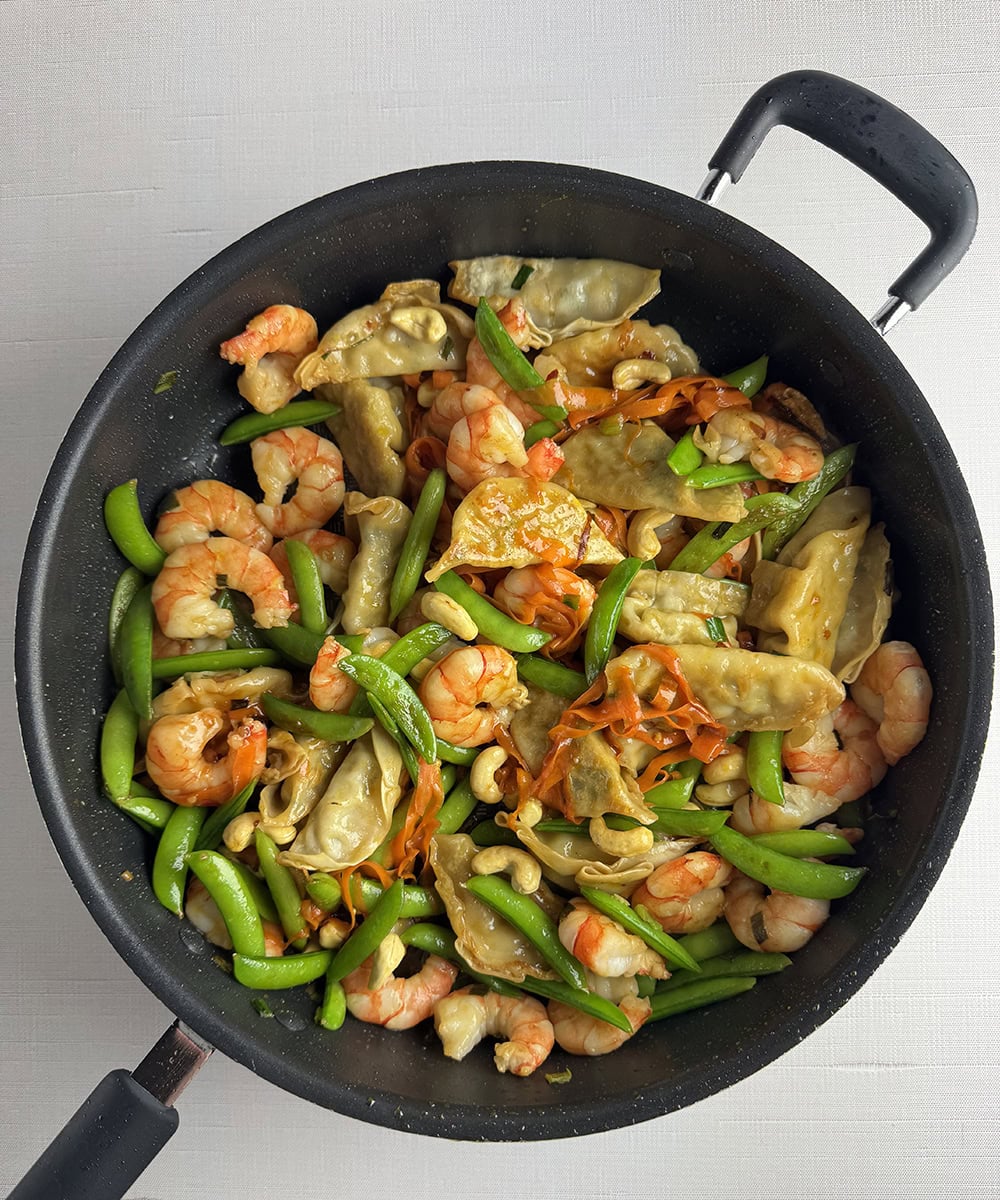 Shrimp dumpling stir-fry in a skillet.