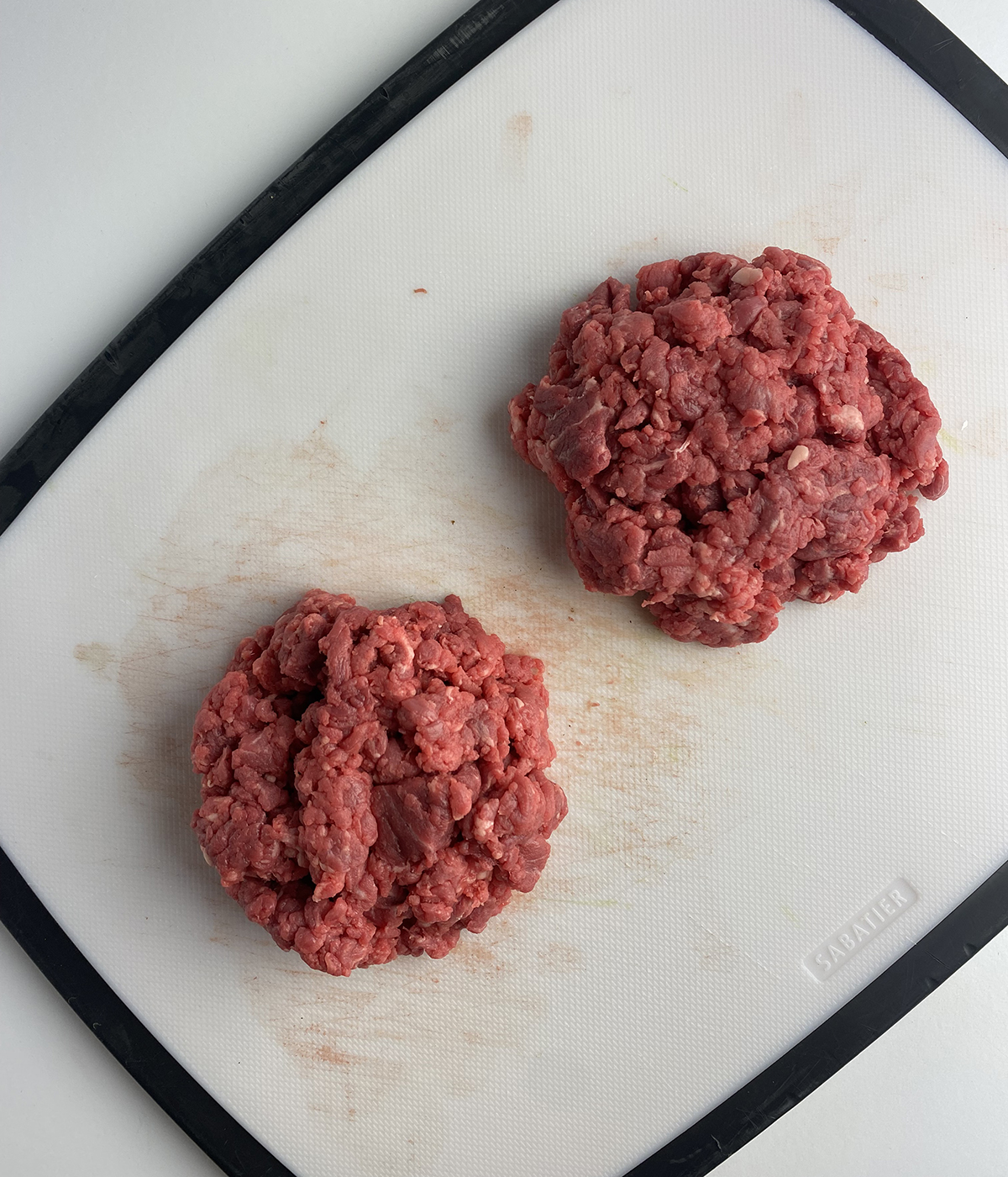 Steak Tartare burgers on a cutting board ready for the skillet.
