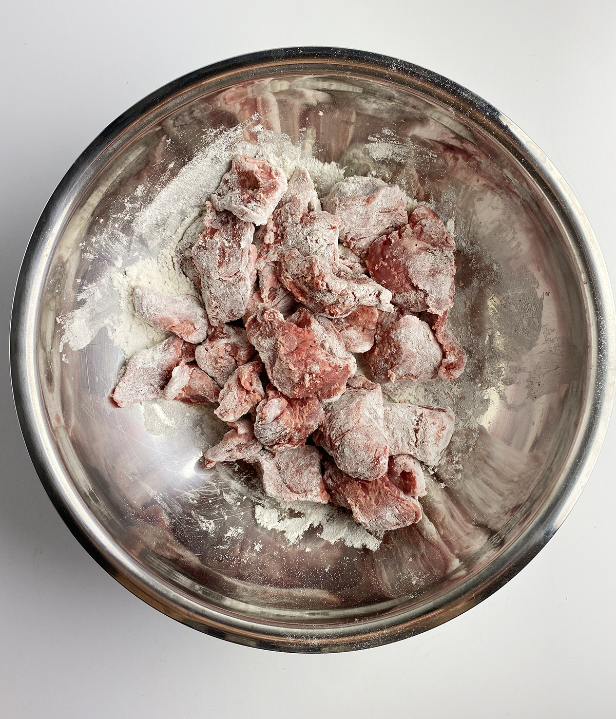 Flour dredged beef stew meat in a bowl.