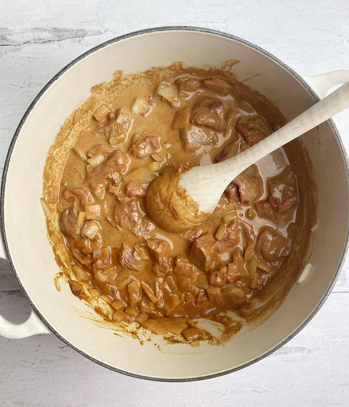 Coconut beef stew with meat stirred in a pot.