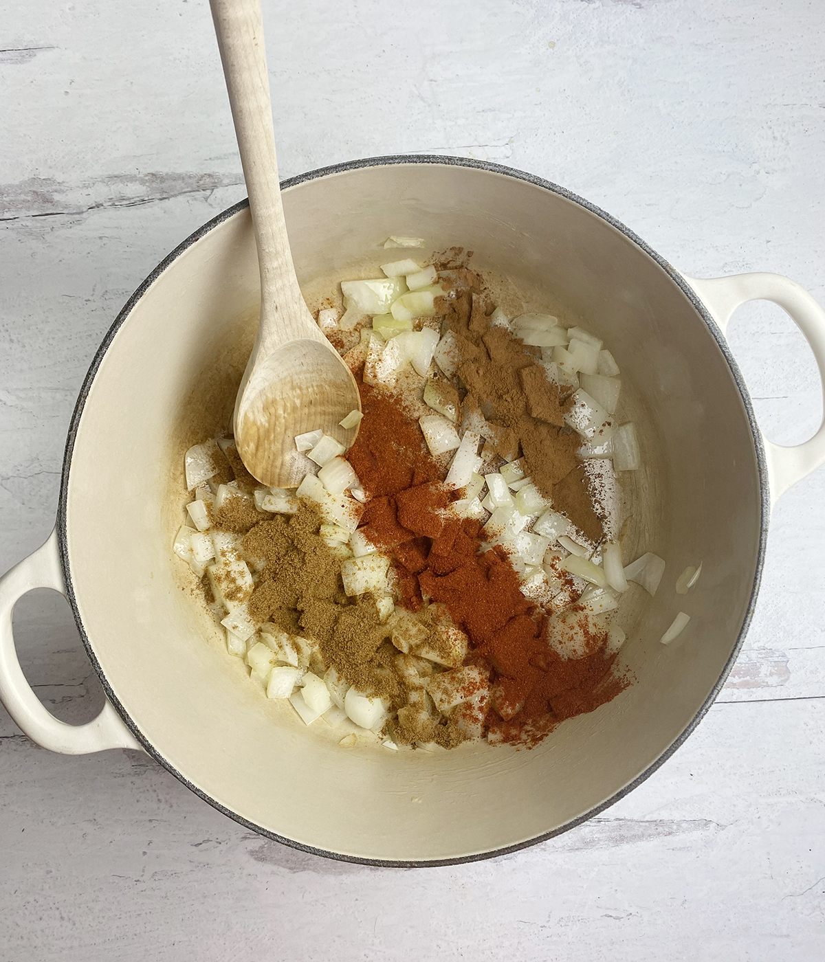 Spices and chopped onion in a pot.