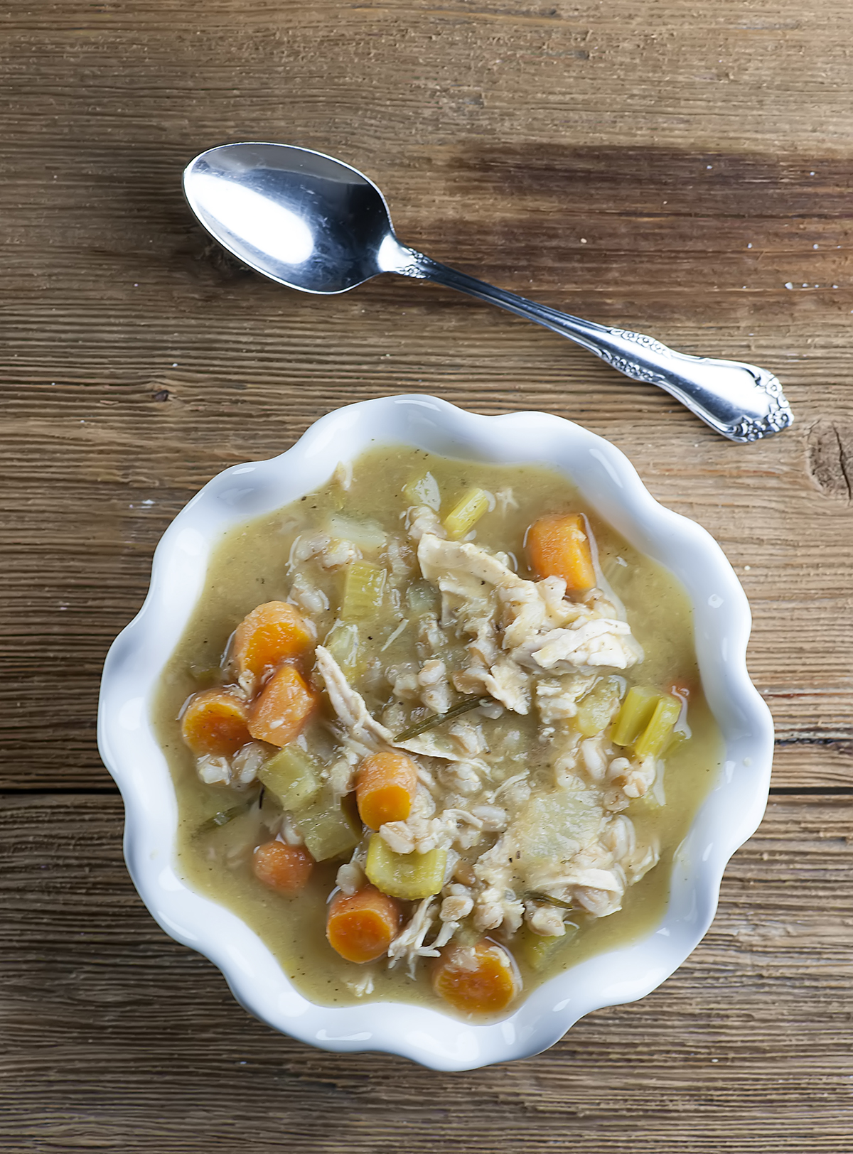 Rosemary chicken soup in a bowl with a spoon.