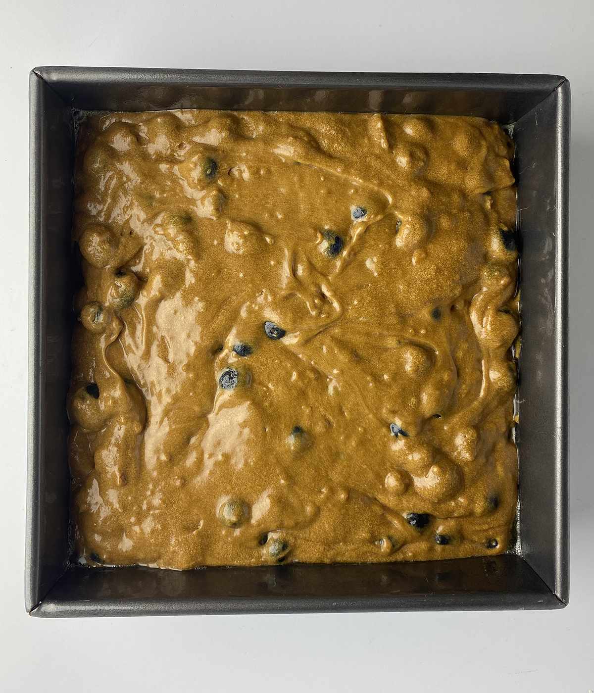 Blueberry molasses cake batter in a pan.