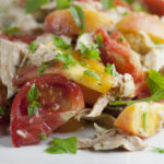 Tomato peach chicken salad ingredients on a plate.