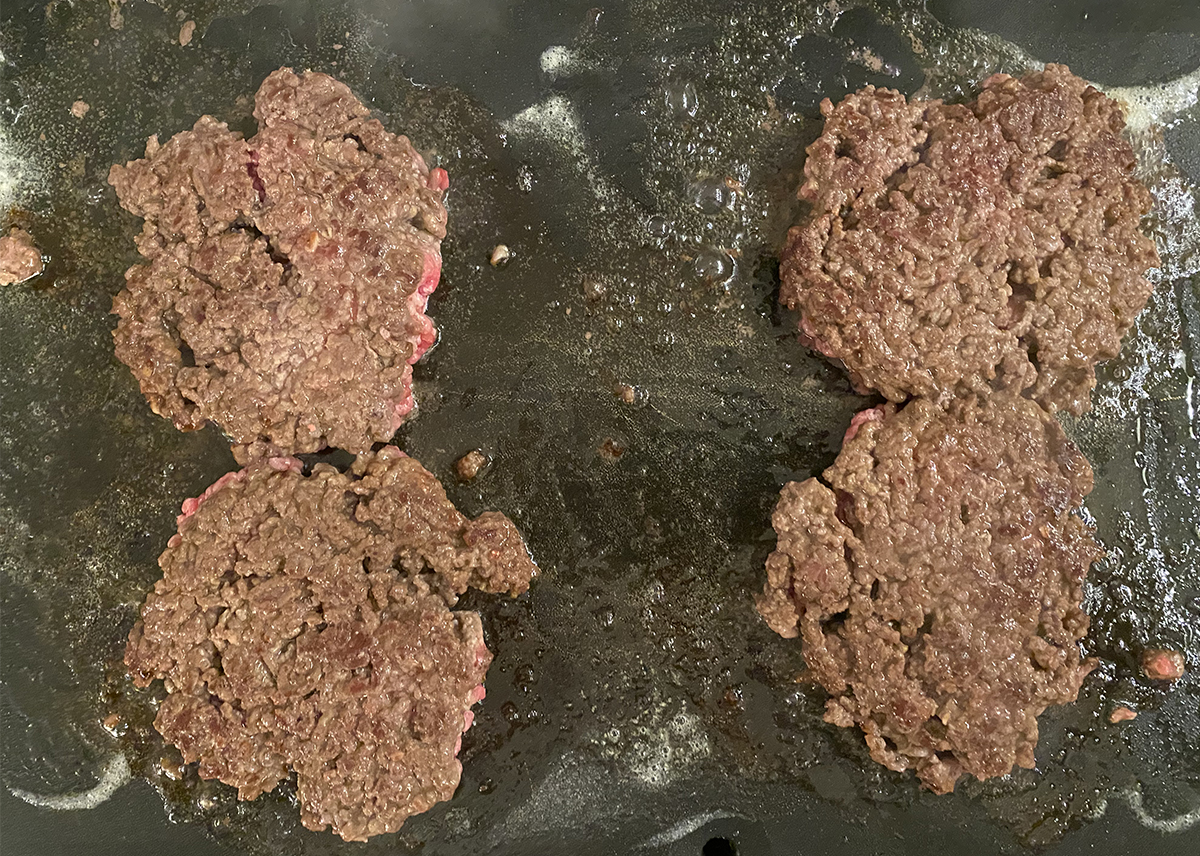 Flipped diner burgers on a griddle.