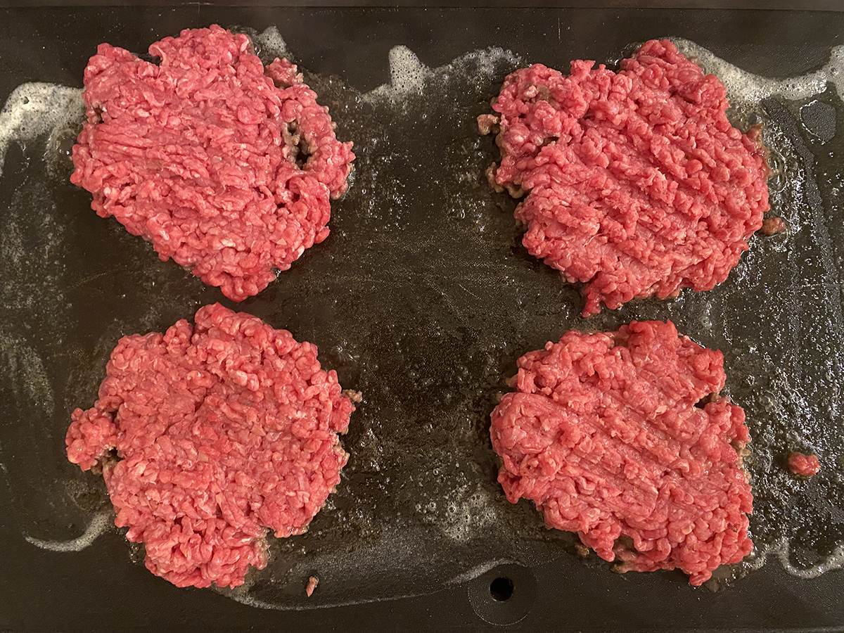 Smashed diner burgers on griddle.