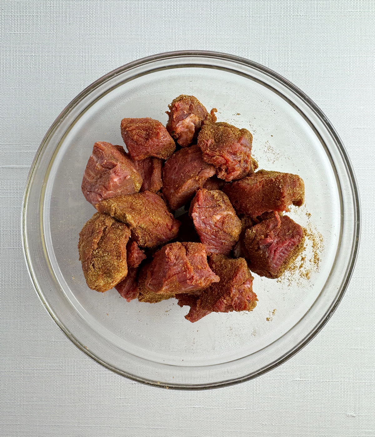 Steak cubes coated with spice rub in a bowl.