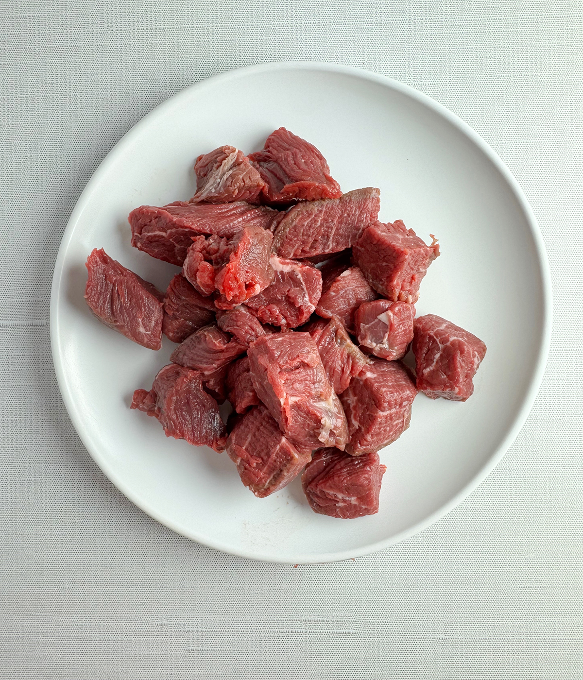 Steak cut into cubes in a bowl.