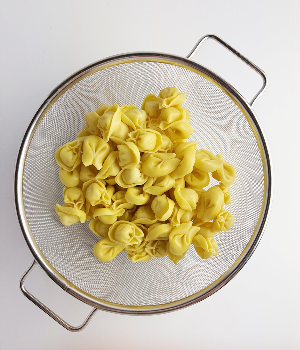 Tortellini draining in a strainer.
