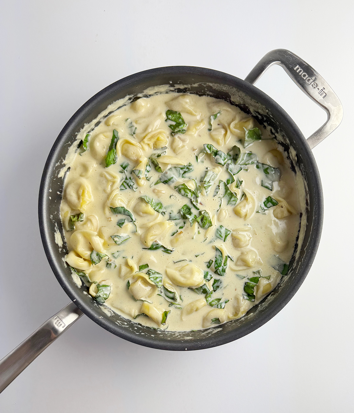 Tortellini with cream sauce in a skillet.