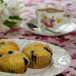 Maple blueberry muffins on a plate with a cup of tea.