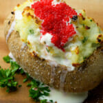 Caviar topped potato on a wooden plate.