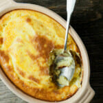 Baked mashed potatoes in a casserole dish with a spoon.